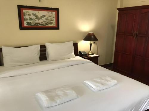 a large white bed with two white towels on it at Hihotel Saraburi in Sara Buri