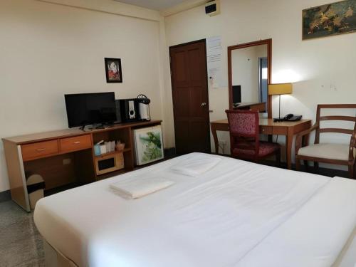 a bedroom with a bed and a desk and a tv at Hihotel Saraburi in Sara Buri