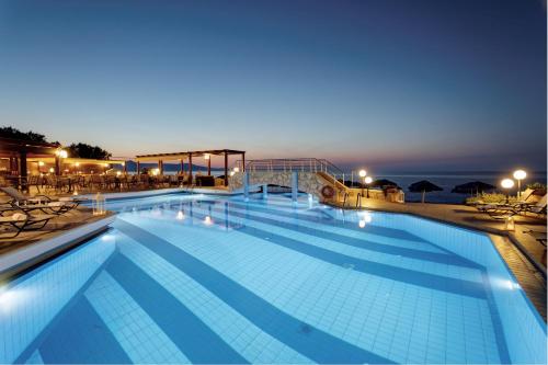 a large swimming pool at night with the ocean in the background at Indigo Mare in Plataniás