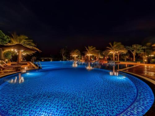 a large swimming pool at night with palm trees at HON BA LAGI BEACH RESORT in La Gi