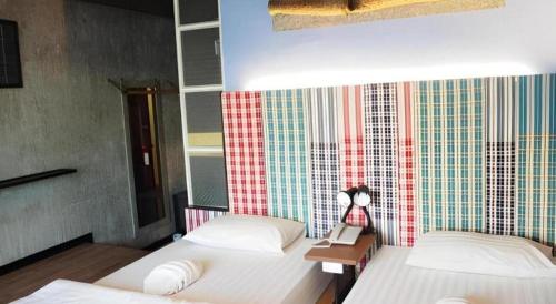 a bedroom with two beds and a wall with colorful tiles at Cactus Resort & Hotel in Khon Kaen
