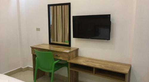 a bedroom with a desk and a tv and a green chair at Hotel Primera in Zamboanga