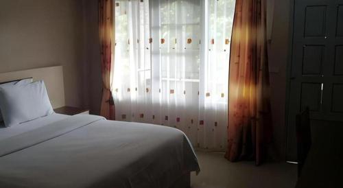 a bedroom with a white bed and a window at Samosir Cottages Resort in Tuk Tuk