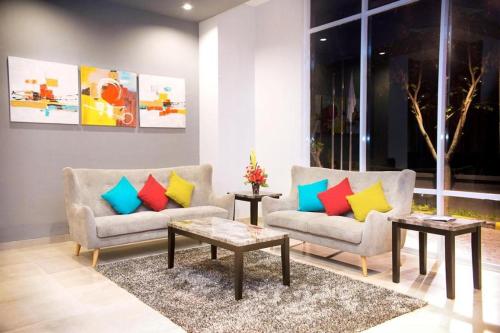 a living room with two couches and two tables at Ayola First Point Hotel Pekanbaru in Pekanbaru