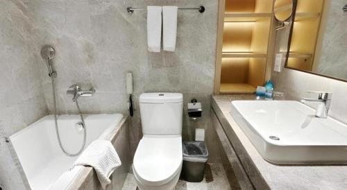 a bathroom with a toilet and a tub and a sink at Dalian Bohai Pearl Hotel in Dalian