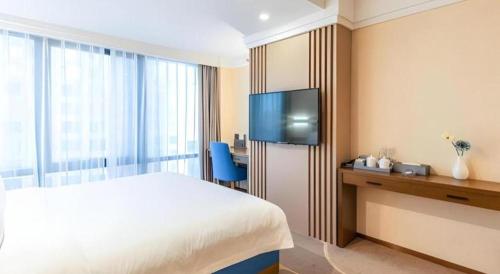 a hotel room with a bed and a flat screen tv at Dalian Bohai Pearl Hotel in Dalian