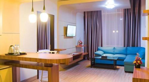 a living room with a blue couch and a table at Ayola First Point Hotel Pekanbaru in Pekanbaru