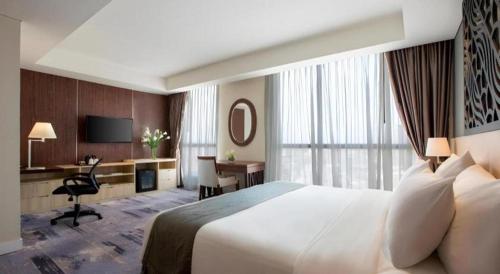 a hotel room with a large bed and a desk at Hotel Grandhika Pemuda in Semarang
