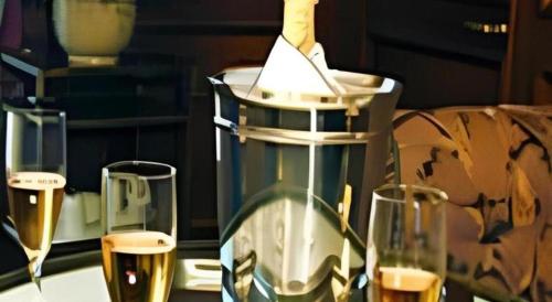 three glasses of wine on a table with a bottle of wine at Hotel Castle Salam in Khulna