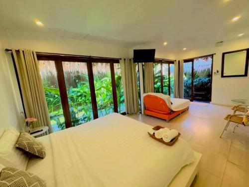 a bedroom with a bed and a chair and windows at The bora bora - Bed and Dream เดอะ โบรา โบร่า - เบด แอนด์ ดรีม in Ban Chek