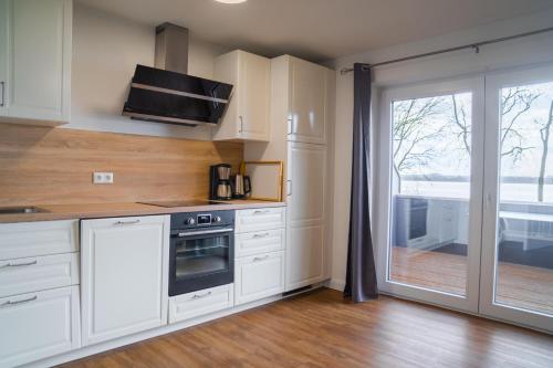 a kitchen with white cabinets and a sliding glass door at Appartementhaus Schleiblick in Kappeln
