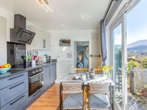 a kitchen with a table and chairs and a window at Hyfrydle Cottage in Pen-y-groes