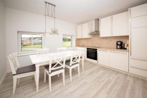 a kitchen with white cabinets and a table and chairs at Appartementhaus Schleiblick in Kappeln