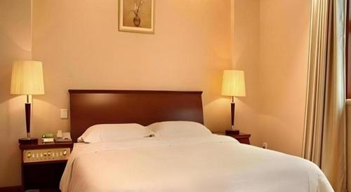 a bedroom with a large white bed with two lamps at Shaanxi Business Hotel in Shanghai