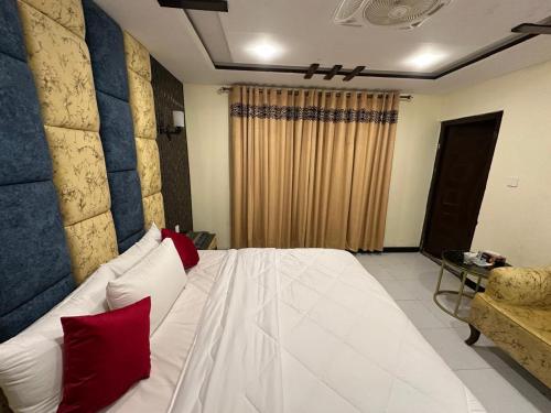 a bedroom with a white bed with red pillows at Decent Luxury Hotel Skardu in Skardu