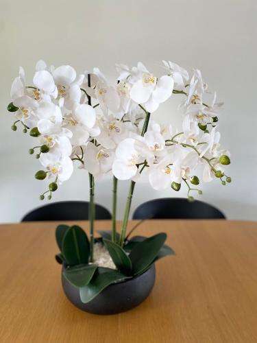 a black vase with white flowers on a table at Villa Paradisiaque au cœur de Grand Baie in Mauritius