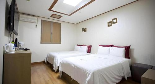 a hotel room with two beds and a television at Chuncheon World Hotel in Chuncheon
