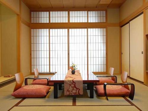 a large room with a table and chairs and windows at Kamiyamada Hotel in Chikuma