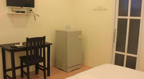 a room with a refrigerator and a table and a chair at Le Bar Tarry Hotel in Loei