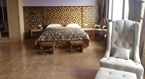 a bedroom with a bed and a white chair at Fafa Hill Hotel and Resort in Bogor