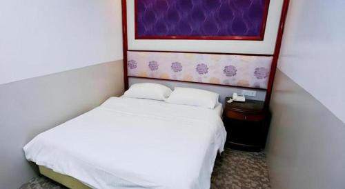 a small bedroom with a bed and a painting on the wall at Hotel 165 in Singapore