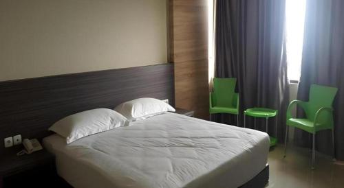 a bedroom with a bed and two green chairs at Fafa Hill Hotel and Resort in Bogor
