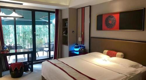 a bedroom with a bed and a view of a balcony at Yuan Culture Hotel Shenzhen World Shajing in Shenzhen