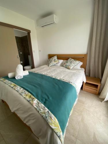 a bedroom with a bed with a green blanket on it at Villa Paradisiaque au cœur de Grand Baie in Mauritius