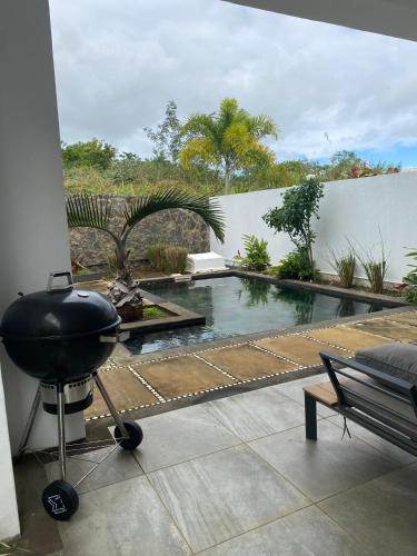 a patio with a grill and a swimming pool at Villa Paradisiaque au cœur de Grand Baie in Mauritius