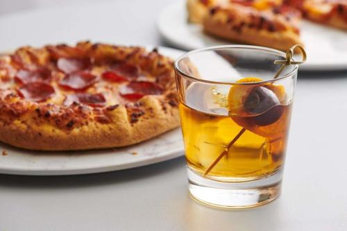a glass of drink next to a pizza on a plate at Hyatt House Fishkill-Poughkeepsie in Fishkill