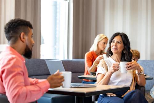 a group of people sitting at a table with cups of coffee at Hyatt Place Atlanta / Alpharetta / Windward Parkway in Alpharetta
