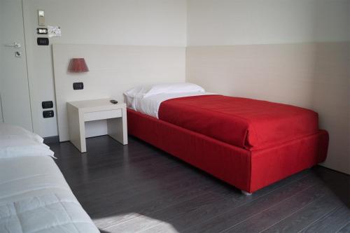 a red bed in a small room with a table at Areté Luxury Room in Reggio Calabria