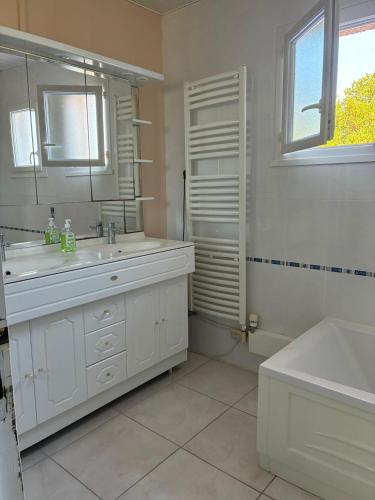 une salle de bain blanche avec un lavabo et un miroir dans l'établissement Villa La Hume proche port plage commodités Bassin d'Arcachon avec piscine chauffée, à Gujan-Mestras