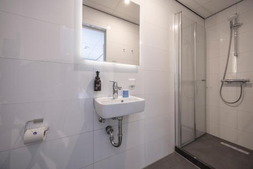 a white bathroom with a sink and a shower at Fletcher Hotel-Restaurant Het Witte Huis in Amersfoort