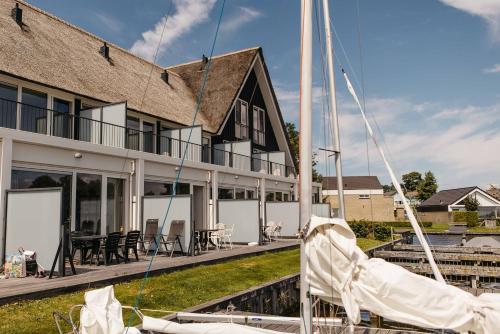 a boat is docked in front of a building at Herenhuis geschakeld | 6 personen - Boutique Parc Pharshoeke in Heeg