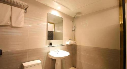 a white bathroom with a sink and a mirror at Jeju Sejong Hotel in Jeju