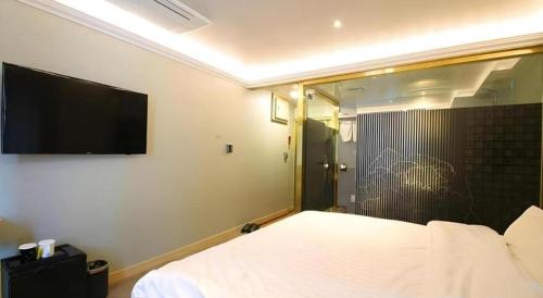 a bedroom with a bed and a tv on the wall at Jeju Sejong Hotel in Jeju