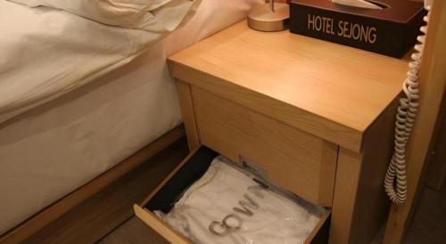 a drawer in a night stand next to a bed at Jeju Sejong Hotel in Jeju