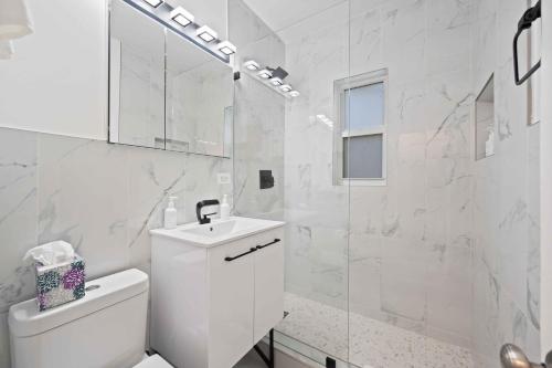 a white bathroom with a toilet and a sink at Condo by the Beach King Bed Lush Patio w BBQ Breakers Key Three H0MES in Fort Lauderdale