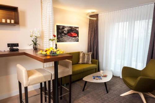 a hotel room with a green couch and a table at Best Western Hotel Hohenzollern in Osnabrück