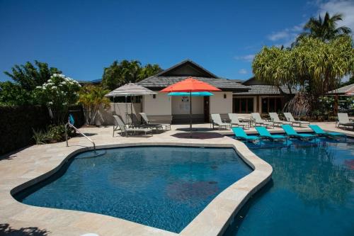a swimming pool with chairs and an umbrella at SEA TO SKY Stunning 3BR Villages Home With Three Master Suites in Waikoloa