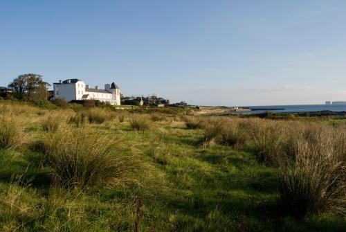 a field of grass with a house in the background at Stella Maris Shore House in Ballycastle