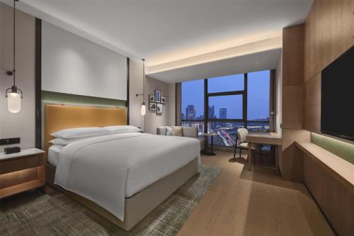 a bedroom with a large white bed and a desk at Doubletree By Hilton Zhengzhou East in Zhengzhou
