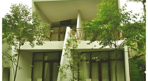 a white building with a balcony with trees in front of it at VillaTel Salse in Bandung