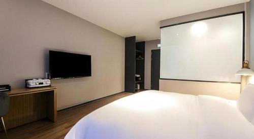 a bedroom with a large bed and a flat screen tv at Gimhae Perfect Hotel in Gimhae
