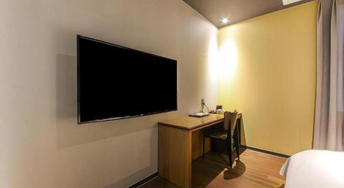 a room with a desk and a television on a wall at Gimhae Perfect Hotel in Gimhae