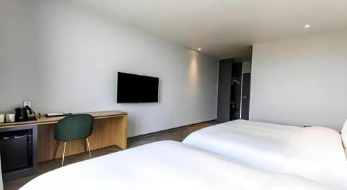 a hotel room with two beds and a desk and a television at Gimhae Perfect Hotel in Gimhae