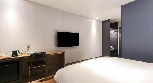 a hotel room with a bed and a desk with a television at Gimhae Perfect Hotel in Gimhae