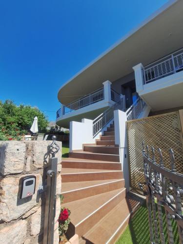 a house with wooden stairs and a stone wall at Solena in Tsikalariá