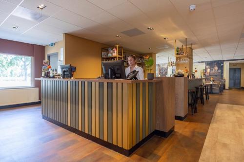 a woman standing at a bar in a restaurant at Fletcher Hotel-Restaurant Het Witte Huis in Amersfoort